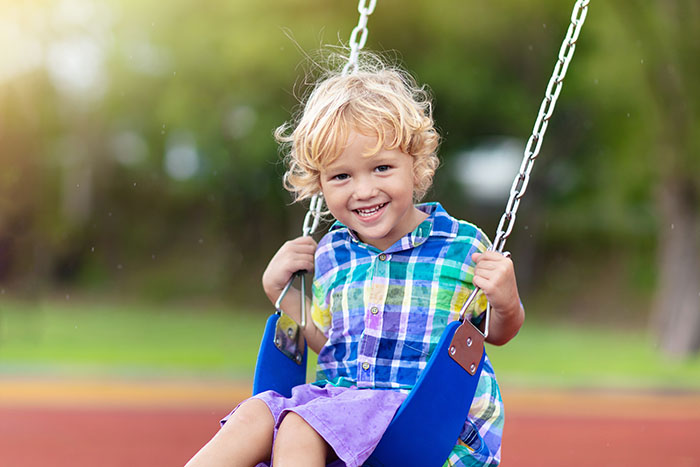 smiling boy on swings at playground at a Preschool & Daycare Serving North Hollywood, Santa Monica & Van Nuys, CA