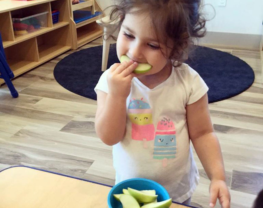 toddler girl eating apple at a Preschool & Daycare Serving North Hollywood, Santa Monica & Van Nuys, CA
