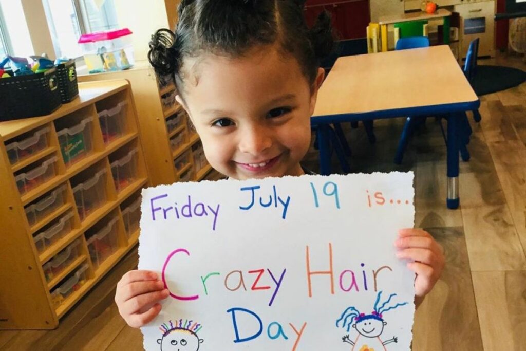 smiling girl holding up paper at a Preschool & Daycare Serving North Hollywood, Santa Monica & Van Nuys, CA