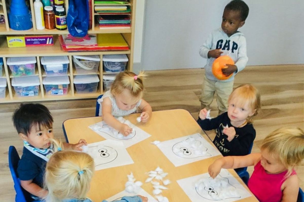 Group of kids boys and girls sit by the table and draw images